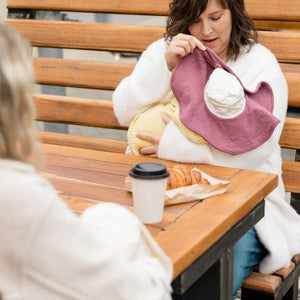 mom using the mobobaby nursing cover and hat to breastfeed baby