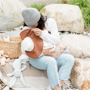 mom using the mobobaby nursing cover and hat to breastfeed baby